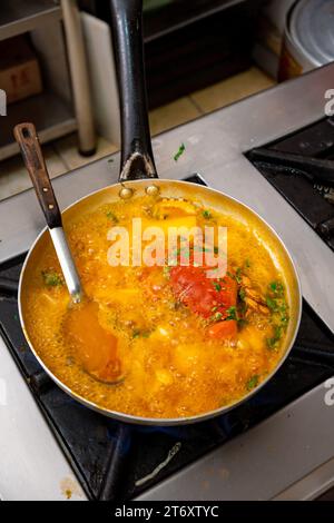 A close-up image of a pan of delicious-looking food boiling on the hob of a modern stovetop Stock Photo