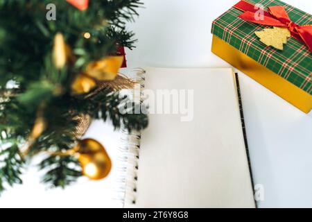 open notepad with blank sheet for wish list text. decorated christmas tree on background Stock Photo
