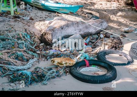 Different kind of garbage at high tide water line on sand beach - ropes, plastic bottles, gummy tires, environmental pollution, Thailand Stock Photo