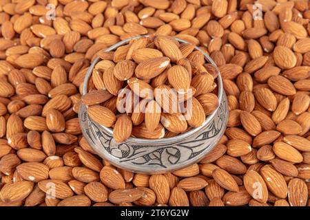 Close-up view of raw almonds without shells from above. Close-up raw brown almond seeds in copper bowl isolated on white background. Top view. It was Stock Photo