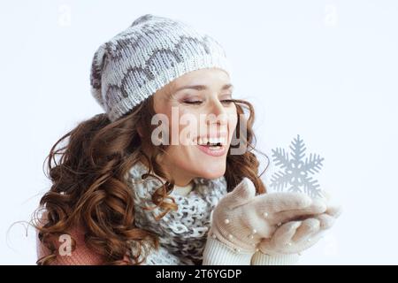 Hello winter. smiling modern 40 years old woman in sweater, mittens, hat and scarf with snowflake isolated on white. Stock Photo