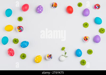 Easter eggs with candies flowers scattered white table Stock Photo