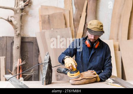 Man sanding wood with orbital sander workshop Stock Photo