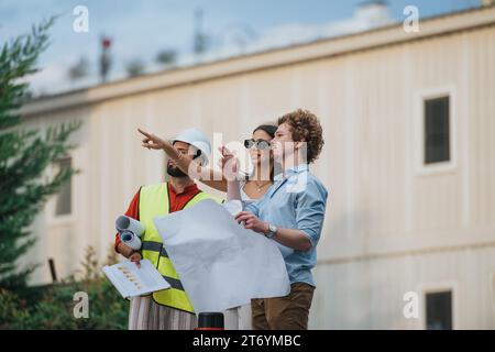 Architects and engineers discuss a building blueprint outdoors in the city. Stock Photo