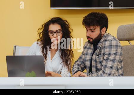 A successful couple in a corporate office collaborate on growth strategies and productivity, sharing ideas and knowledge to ensure success. Stock Photo