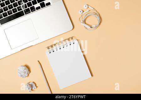 Crumpled paper notepad pencil earphone laptop beige background Stock Photo