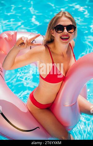Woman flamingo swim ring pool party Stock Photo
