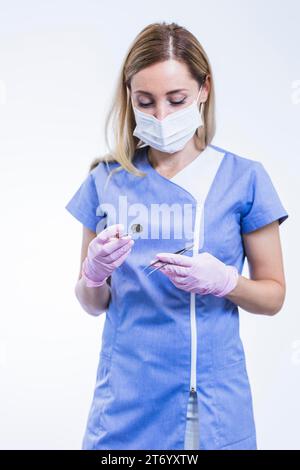 Young female dentist holding forceps dental mirror Stock Photo