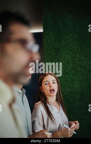 Multiracial Business Group Collaborating in Creative Co-Working Space. Glass Wall Covered in Sticky Notes With Statistics and Ideas. Stock Photo