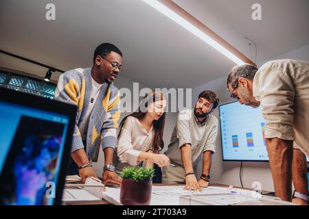 Multiracial Team of Architects and Engineers Collaborating on Project Blueprint in a Corporate Board Room Stock Photo