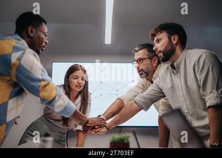 Business Meeting in a Multicultural Office: Collaborating on Architectural Blueprints, Putting Hands Together. Stock Photo