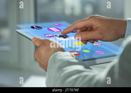 Marketing strategy. Man using tablet computer with virtual screen and icons indoors, closeup Stock Photo