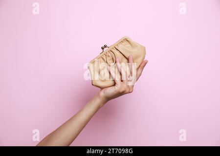 Woman holding leather purse on pink background, closeup Stock Photo