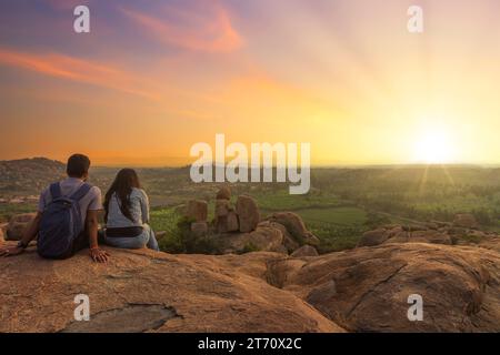 Tourist couple enjoy sunset view  from top a hill at Hampi Karnataka, India Stock Photo