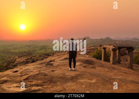 A woman tourist enjoy aerial mountain landscape view of Hamp at sunset at Karnataka India Stock Photo