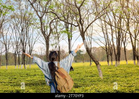 Young female tourist exults in joy with raised arms while standing in a tea plantation at Darjeeling, India. Stock Photo