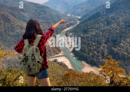 Young girl tourist enjoys a scenic aerial view of Teesta river and Himalayan landscape from Lover's Point at Darjeeling, India. Stock Photo