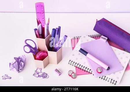 Holder with different stationery and notebooks on light desk Stock Photo