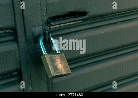 Locked padlock hanging on the green metal gate in Brazil Stock Photo