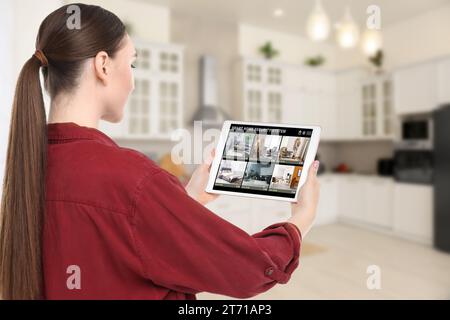 Woman using smart home security system on tablet computer indoors. Device showing different rooms through cameras Stock Photo