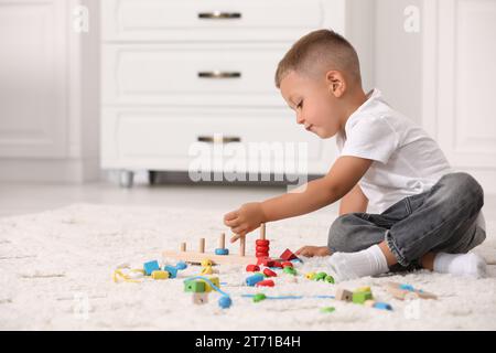 Motor skills development. Little boy playing with stacking and counting game on floor indoors Stock Photo