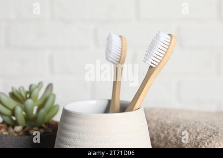 Bamboo toothbrushes in holder on blurred background, closeup Stock Photo