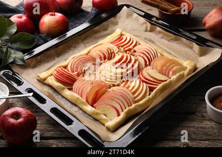 Baking tray with uncooked apple galette and ingredients on wooden table, closeup Stock Photo