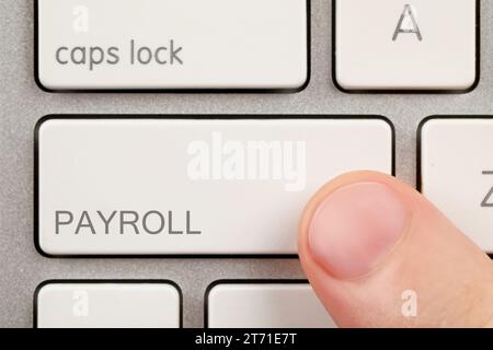 Man pressing button with word Payroll on keyboard, top view Stock Photo