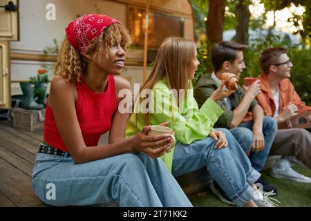 Happy group of friend sitting in row eating snacks rest during picnic Stock Photo