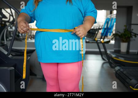 Closeup waistline of overweight woman wrapped in measuring tape Stock Photo