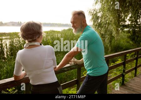 Happy elderly woman and man friends having nice conversation resting after run Stock Photo