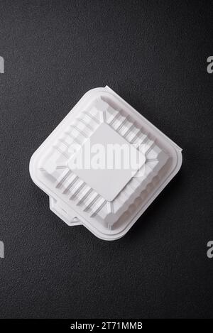 Square plastic or cardboard container of white color for food on a dark concrete background Stock Photo