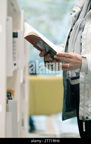 Woman standing in the corridor of the library reading a book. Empty copy space for Editor's text. Stock Photo