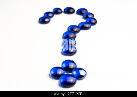 Detail view of  question mark drawn with blue stones on white background; Detail view of  question mark drawn with blue stones on white background Stock Photo
