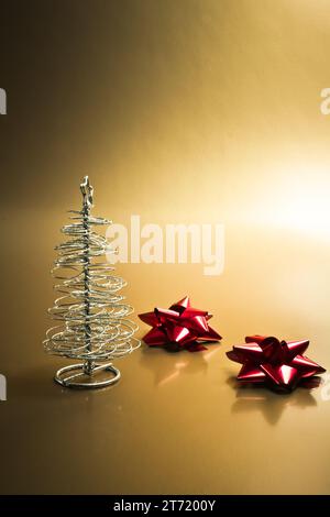 detail of silver christmas tree with red bows on gold background; detail of silver christmas tree with red bows on gold background Stock Photo