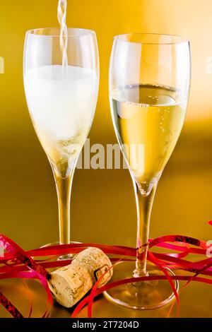 close up a pair of champagne flutes with decoration on golden background Stock Photo