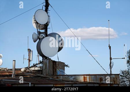 Telecommunication antenna with multiple satellite dishes against the blue sky Stock Photo