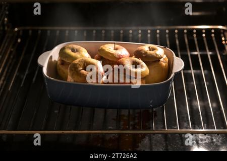 Steaming baked apples in the oven, stuffed with almonds, honey and cinnamon, preparation for a holiday dessert on thanksgiving, Christmas or new year, Stock Photo