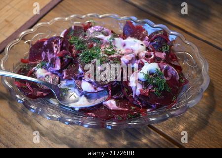 Red beet salad with a creamy dressing and dill garnish, healthy vegetarian dish in a glass bowl, selected focus, narrow depth of field Stock Photo