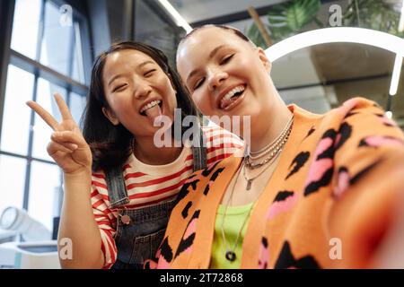 POV of smiling young woman with creative hair taking selfie photo in beauty salon and making faces Stock Photo