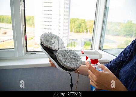 Spraying cleaning agent on the microfibers of a window cleaner robot before starting work. Stock Photo