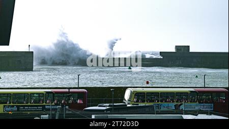 Brighton UK 13th November 2023 - A bus passes by as waves crash over Brighton Marina wall as Storm Debi approaches Britain with weather warnings being issued for parts of the country : Credit Simon Dack / Alamy Live News Stock Photo