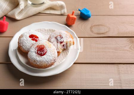 Hanukkah donuts and dreidels on wooden table, space for text Stock Photo