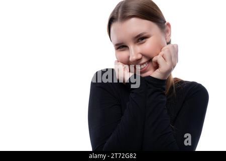 Shy pre-teen girl with blond hair in black clothes on a white background Stock Photo