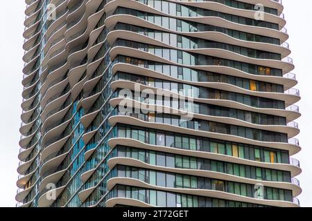 The Aqua Tower's facade in Chicago, Illinois, United States, displays the characteristic wave-shaped, cantilevered balconies that architect Jeanne Gang designed for the roughly 262-metre skyscraper, completed in 2009. Regarded as the first skyscraper in the world designed by a woman, the building is accented with shimmering blue glass. Individual rooms are already lit. Stock Photo