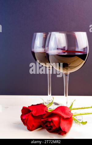 glasses of wine near red roses on old wood Stock Photo