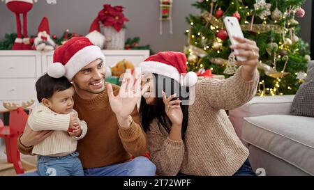 Couple and son having video call sitting on floor by christmas tree at home Stock Photo