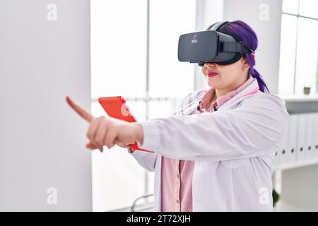 Young beautiful plus size woman doctor using virtual reality glasses at clinic Stock Photo