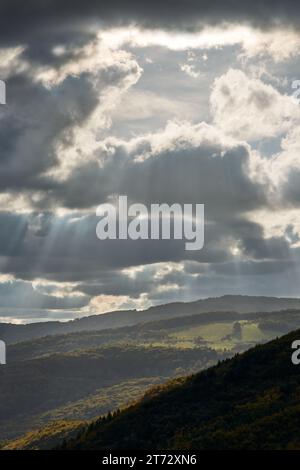 Autumn mountain landscape with dramatic sky. Beautiful sun rays behind the clouds. Illuminating the forest and hills. Dubrava, Slovakia Stock Photo