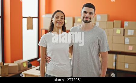 Two smiling workers, man and woman, sharing a heartfelt hug in the office, embodying team spirit Stock Photo
